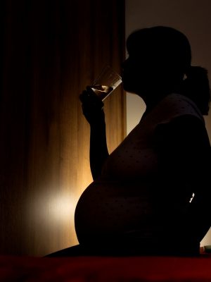 A pregnant woman drinking water in the dark.