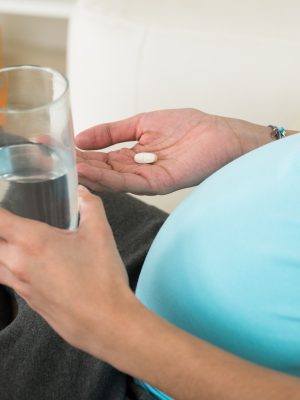 Pregnant woman taking a pill.