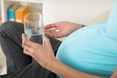 Pregnant woman taking a pill.