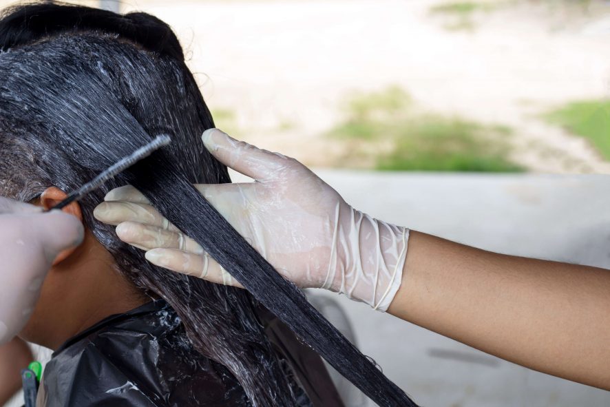 Image of professional dyeing a woman black hair.