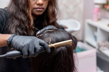 Image of a professional making a new hairstyle to a woman with black hair.