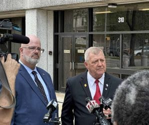 Two men standing and giving an interview for the news.