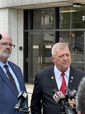 Two men standing and giving an interview for the news.