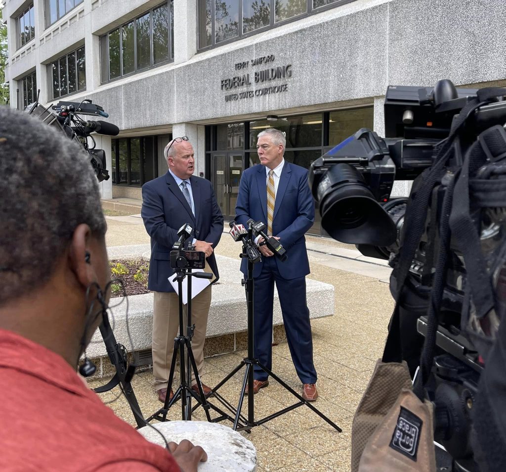 Two men standing and giving an interview for the media.