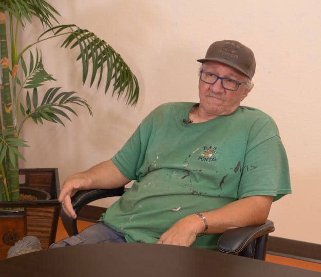 Man pictured from side, sitting and looking in the distence.