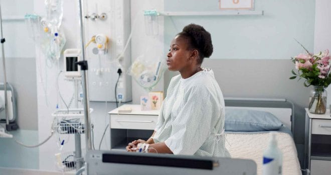 Woman in hospital sitting on her bed.